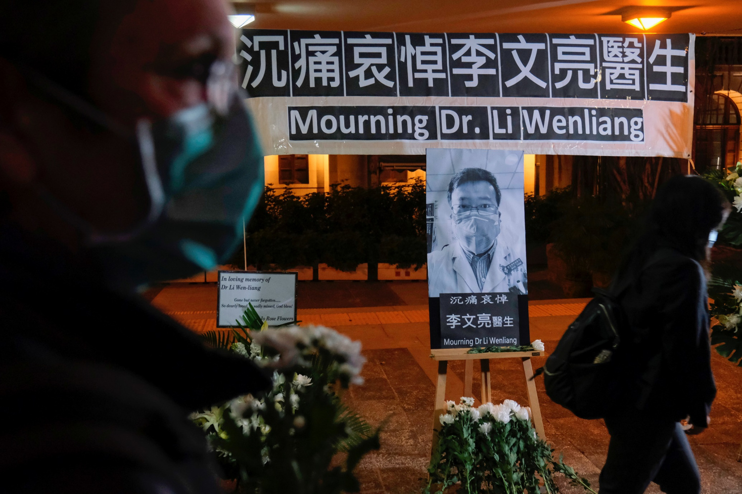 People wearing masks attend a vigil for late Li Wenliang, an ophthalmologist who died of coronavirus at a hospital in Wuhan