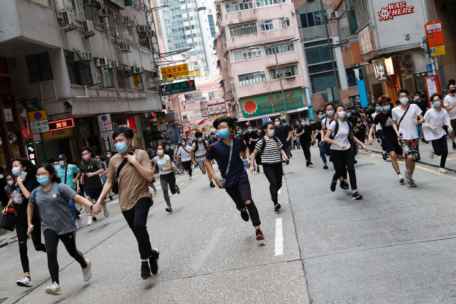 Anti-government protesters run after riot police disperse them in Hong Kong